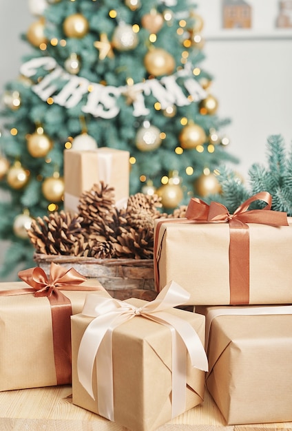 Cajas de regalo y piñas con árbol de Navidad detrás