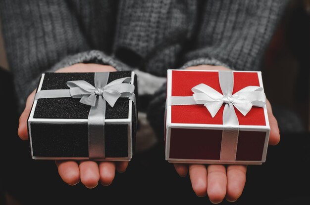 Cajas de regalo en primer plano de manos femeninas Mujer con caja de regalo roja y negra