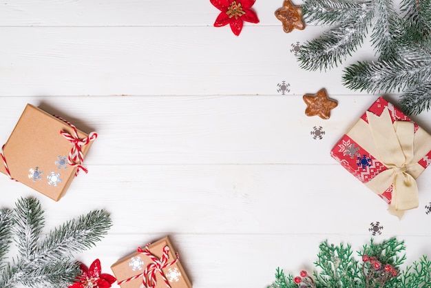 Cajas de regalo con ramas de abeto de nieve y galletas de estrellas en un blanco de madera. Tarjeta de Navidad. Copyspace plano laico