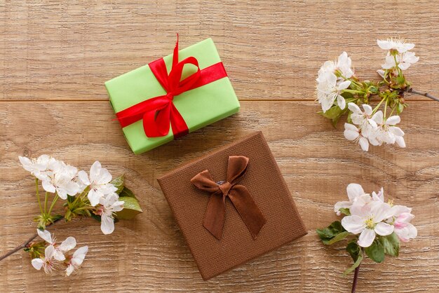 Cajas de regalo con ramas de cerezo en flor y manzano en el fondo de madera Vista superior