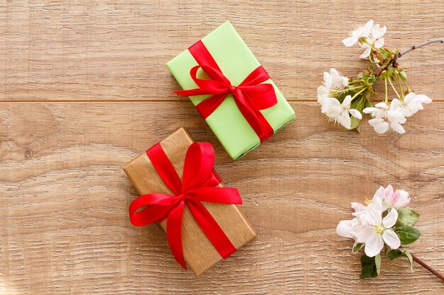 Cajas de regalo con ramas de cerezos en flor y manzanos en el fondo de madera Vista superior