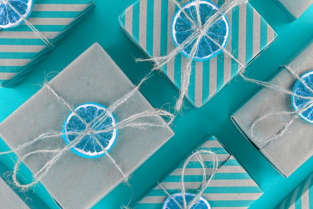 Foto cajas de regalo de rayas naturales y azules, decoradas con naranja seca. disposición oblicua de las cajas una al lado de la otra.