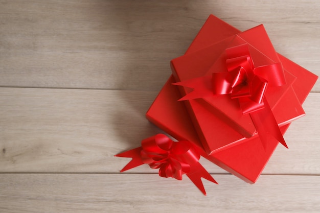 Cajas de regalo rojas y cinta roja sobre fondo de madera con espacio.