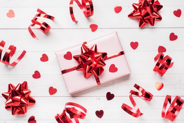 Cajas de regalo rosa con cintas rojas y lazos, corazones de confeti sobre un fondo blanco. Copia espacio Lay Flat. Tarjeta de felicitación para fiesta de cumpleaños, boda de San Valentín.