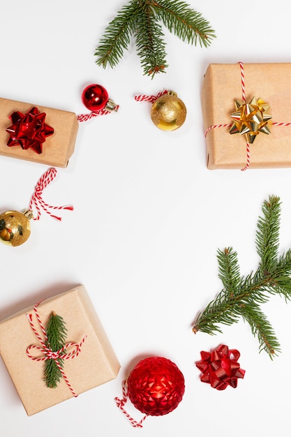 Cajas de regalo sorpresa envueltas en papel artesanal con lazo dorado, abeto y bolas rojas doradas