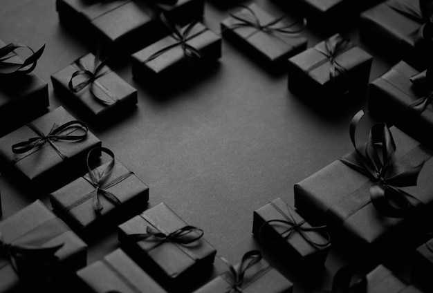 Cajas de regalos dispuestas envueltas en papel negro con cinta negra sobre fondo negro Vista superior concepto de vacaciones de Navidad con espacio de copia en el medio