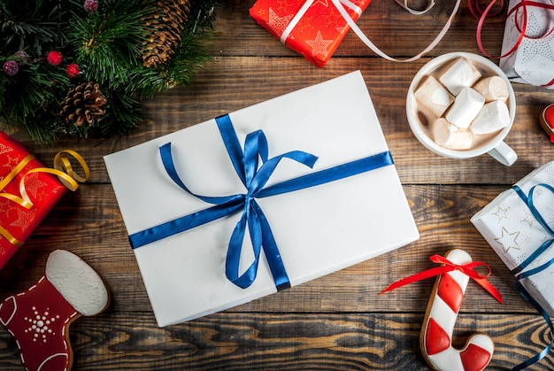 Cajas de regalos de Navidad decoradas con una taza de chocolate caliente, pan de jengibre y ramas de árboles de Navidad.