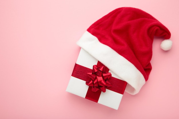 Cajas con regalos de Navidad con sombrero de Santa sobre fondo rosa Vista superior Espacio para texto