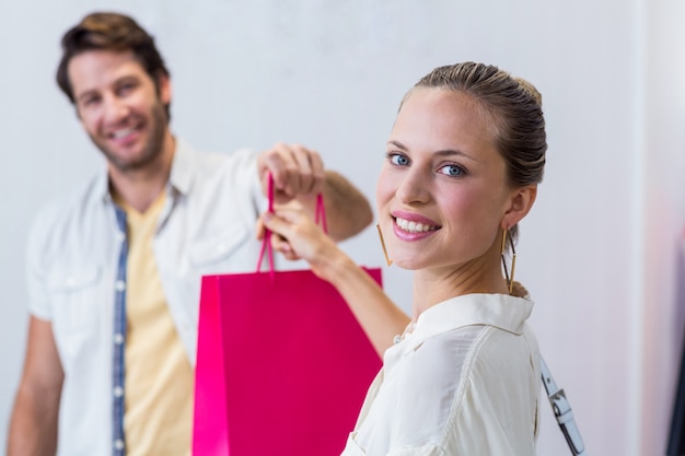 Cajero sonriente que da el bolso de compras a la mujer