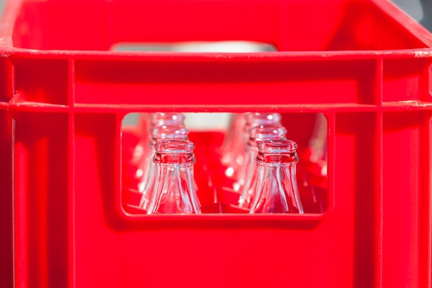 Cajón de plástico rojo con botellas de vidrio vacías. Disparo filtrado horizontal