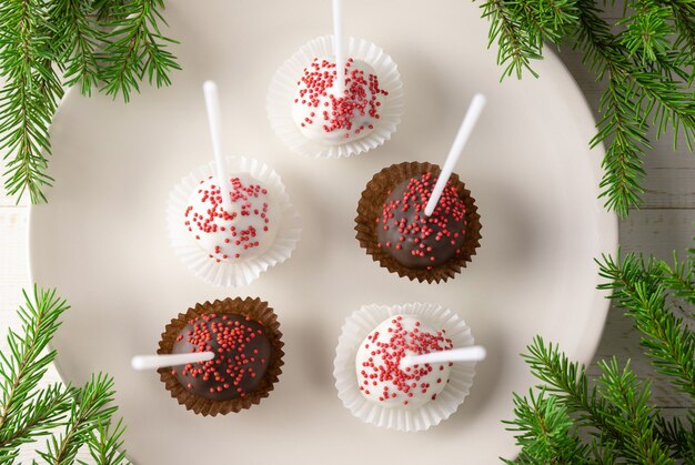 Foto cake pops auf dem teller und weihnachtstannenzweigen.