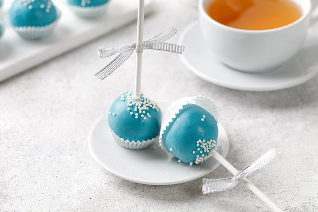 Cake Pops auf Stöcken Satz blauer Cake Pops mit einer Tasse Tee auf grauem Hintergrund Kopierbereich