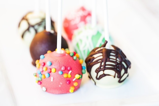 Cake pops de cerca en la placa blanca.