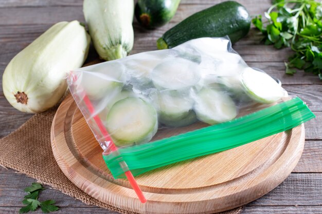 Calabacín congelado en una bolsa de plástico sobre mesa de madera. Concepto de comida congelada
