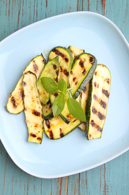 Calabacín a la parrilla en un plato azul con albahaca