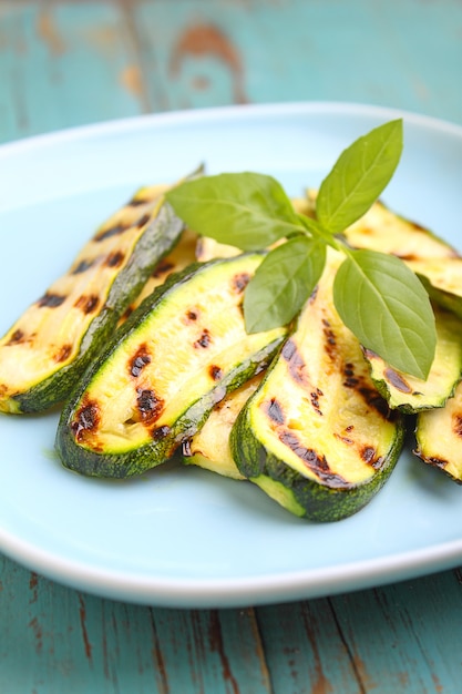 Calabacín a la parrilla en un plato azul con albahaca