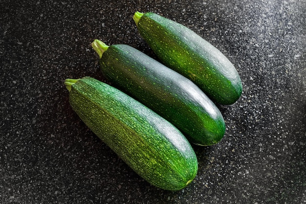 Calabacín rayado verde sobre una superficie de mesa negra Cosecha de verano de verduras