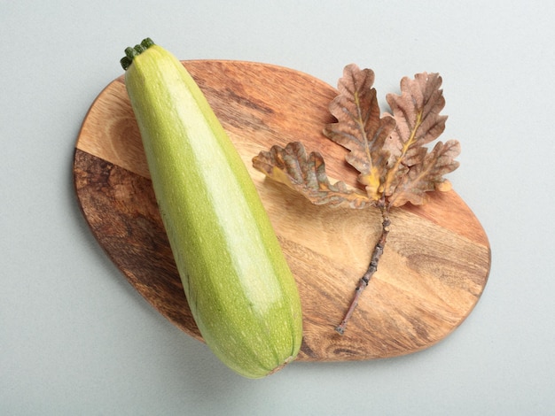 Calabacín en una tabla de cortar de madera sobre un fondo gris