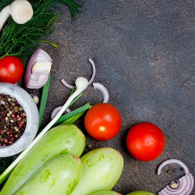 Calabacín, tomates, hierbas y especias jóvenes de la primavera en fondo negro