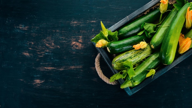 Calabacín verde en una caja de madera Verduras frescas Sobre un fondo de madera negra Vista superior Espacio de copia