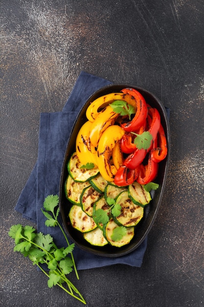 Calabacín de verduras a la plancha, pimiento rojo y amarillo, pimiento morrón y bouquet de cilantro en sartén. Vista superior. Concepto de barbacoa.