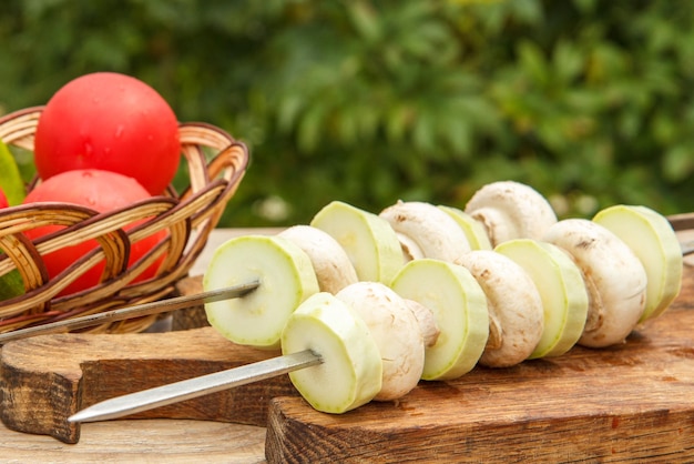 Calabacines y champiñones en brochetas con tomates en una cesta de mimbre