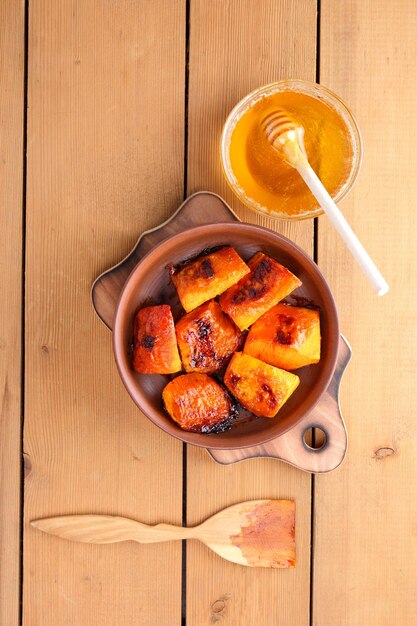 Calabaza al horno en un plato de arcilla Calabaza al horno y miel en una mesa de madera Postre de verduras de otoño en estilo rústico Vista superior Espacio de copia