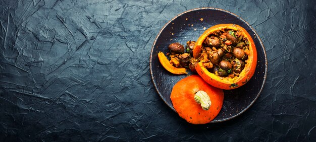 Calabaza al horno rellena de setas y arroz. Comida tradicional de otoño. Copiar el espacio