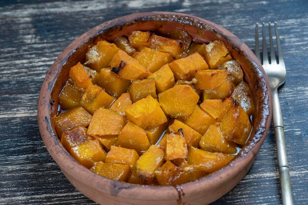 Calabaza amarilla al horno con miel, aceite de oliva y especias en un plato sobre la mesa de madera Comida vegetariana Primer plano