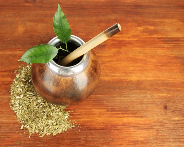 Calabaza y bombilla con yerba mate en mesa de madera