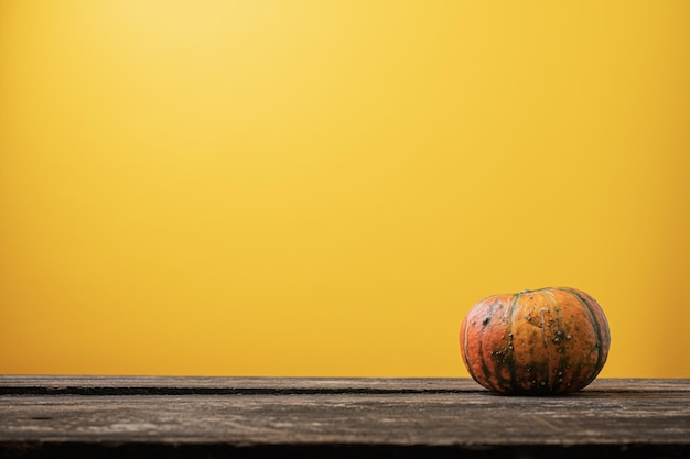 Calabaza de calabaza sobre tabla de madera rústica sobre fondo amarillo otoñal. con mucho espacio para copiar.