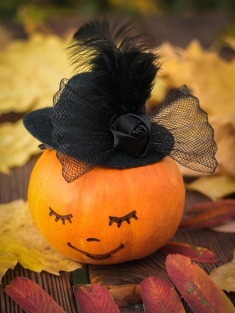 Calabaza con cara en la mesa con hojas de otoño.