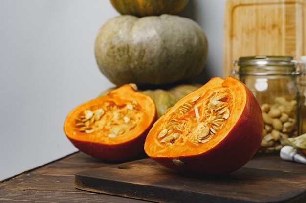 Calabaza cortada en mitades sobre mesa de madera oscura.