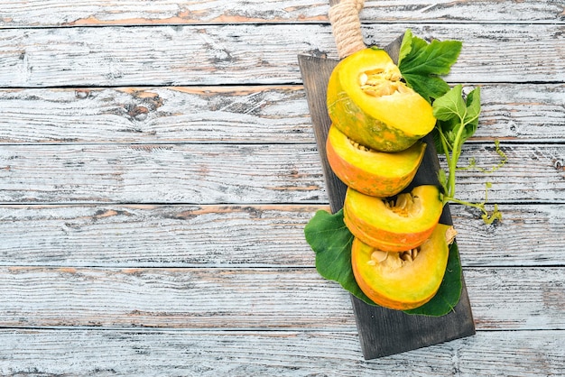 Calabaza cortada con rodajas en una tabla de madera Verduras frescas En una mesa de madera blanca Espacio libre para texto Vista superior