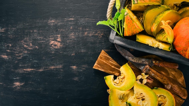 Calabaza cortada con rodajas en una tabla de madera Verduras frescas Sobre un fondo negro Espacio libre para texto Vista superior