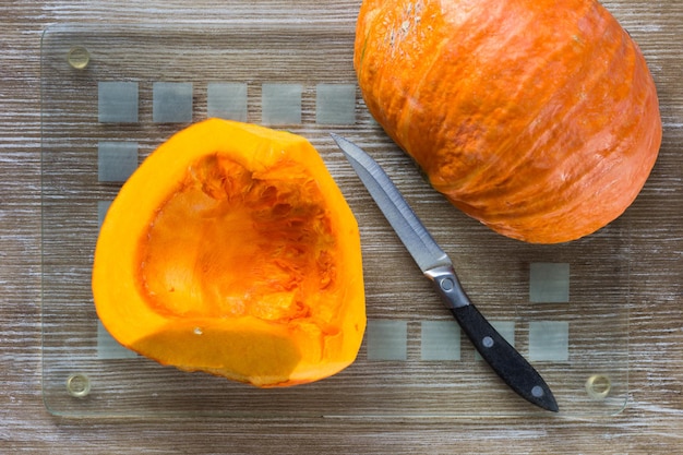 Calabaza cortada en una tabla de cortar de vidrio en el fondo de madera