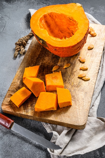 Calabaza cruda fresca en una tabla de cortar, cortada en cubos. Cocina vegetariana