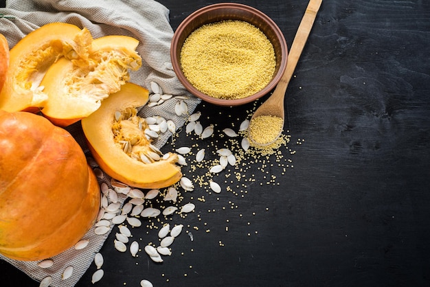 Foto calabaza cruda y semillas de lentejas sobre fondo de madera negra. vista superior. copia espacio