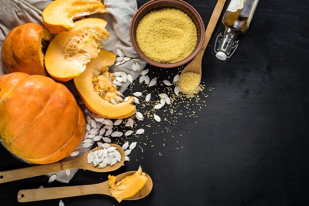 Calabaza cruda y semillas de lentejas sobre fondo de madera negra. Vista superior. copia espacio