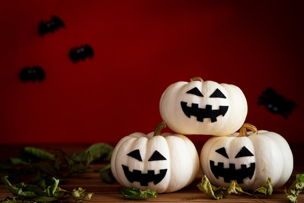 Calabaza fantasma blanco en la mesa de madera con bate sobre fondo naranja