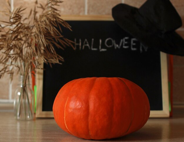 Calabaza fresca de naranja en el fondo de una pizarra con la inscripción en tiza halloween