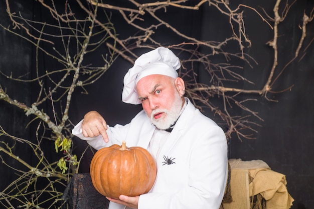 Calabaza grande para chef barbudo de halloween con chef de comida de dieta de calabaza hombre en delantal blanco que presenta