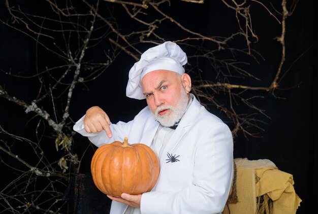 Calabaza grande para cocinero barbudo de halloween con gorro de cocinero con hombre de chef de comida de dieta de calabaza en delantal blanco