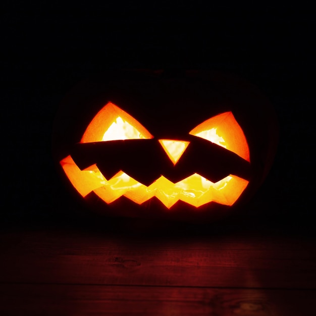 Calabaza de Halloween aterradora brilla en la noche sobre un fondo negro