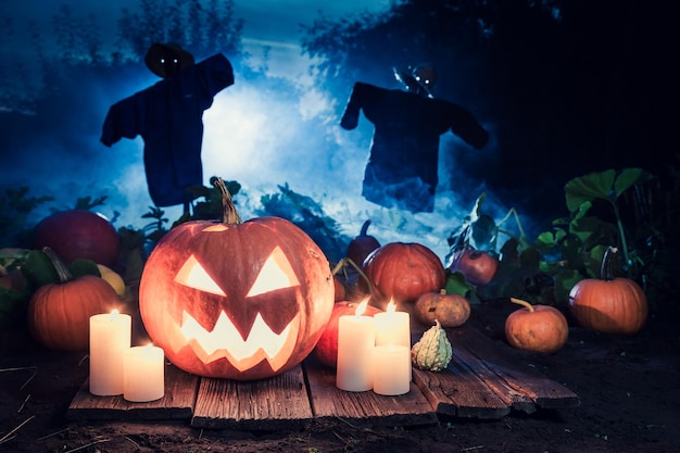 Calabaza de Halloween aterradora con espantapájaros en el campo