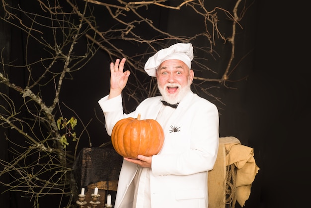 Calabaza para halloween cocinero barbudo con gorro de cocinero con calabaza chef hombre en delantal blanco con calabaza para