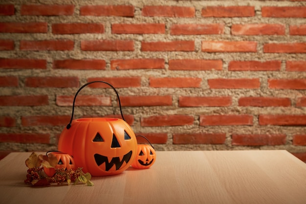 Calabaza de Halloween espeluznante, Jack O Lantern en una mesa de banco de madera y espacio para copiar texto en la pared de ladrillo