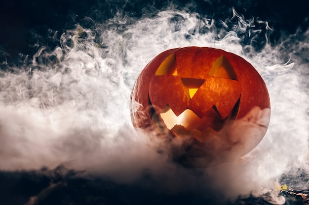 Calabaza de Halloween en humo en el bosque de otoño de noche