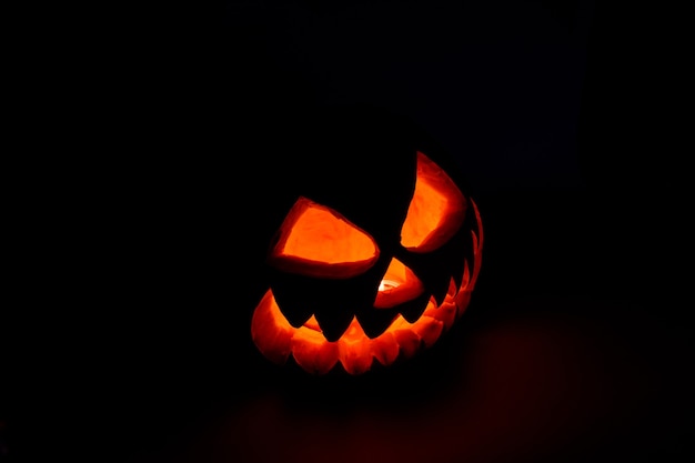 Calabaza de halloween luminosa espeluznante sobre fondo negro