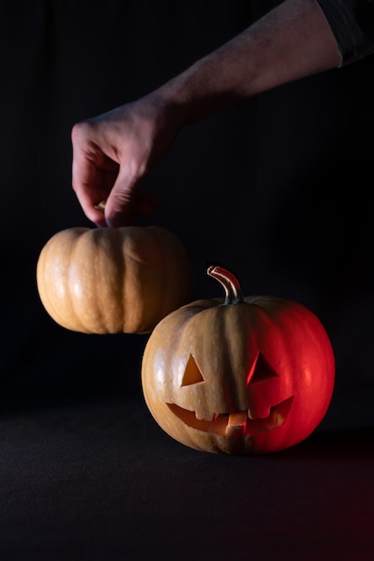 Calabaza de Halloween con mano iluminada sobre fondo negro